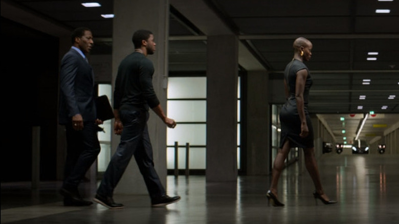 Attache, T'Challa and Ayo walk through a parking garage