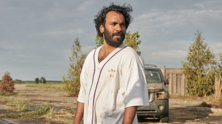 Sayid standing in front of muddy car