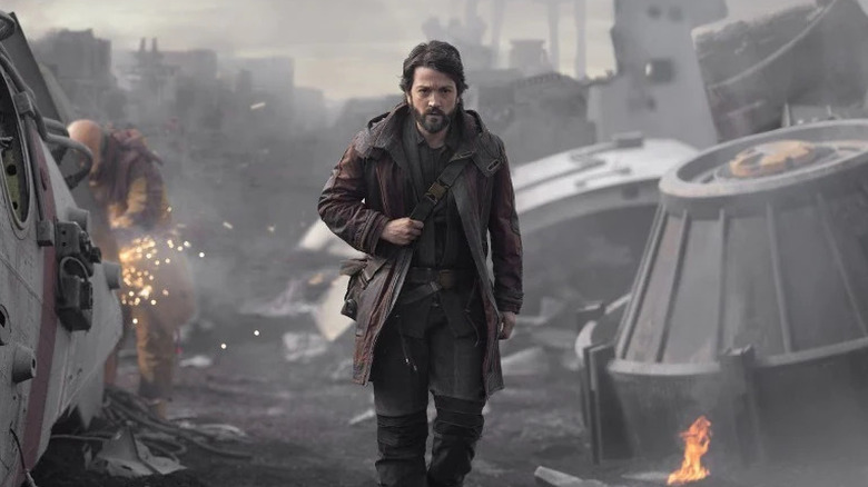 Cassian walks through debris