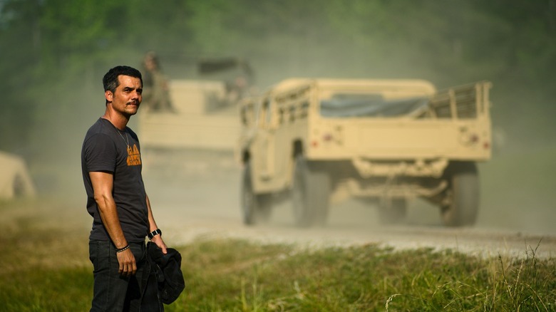 Joel next to army vehicles