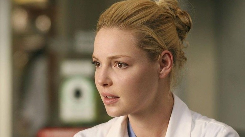 Izzie with her hair in a bun and a white coat looking concerned on Grey's Anatomy