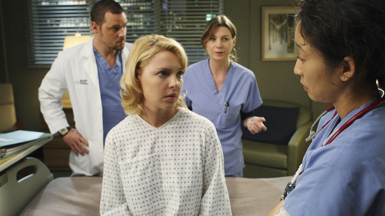 Izzie in a hospital gown and room surrounded by surgical residents on Grey's Anatomy