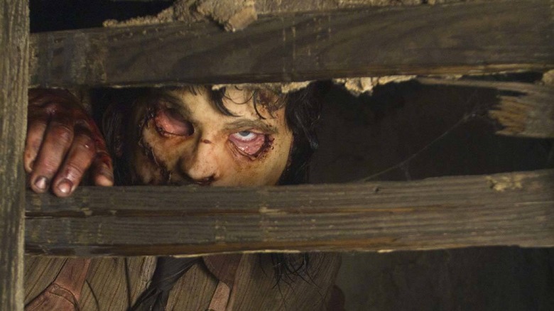 Leatherface peering through wooden slats