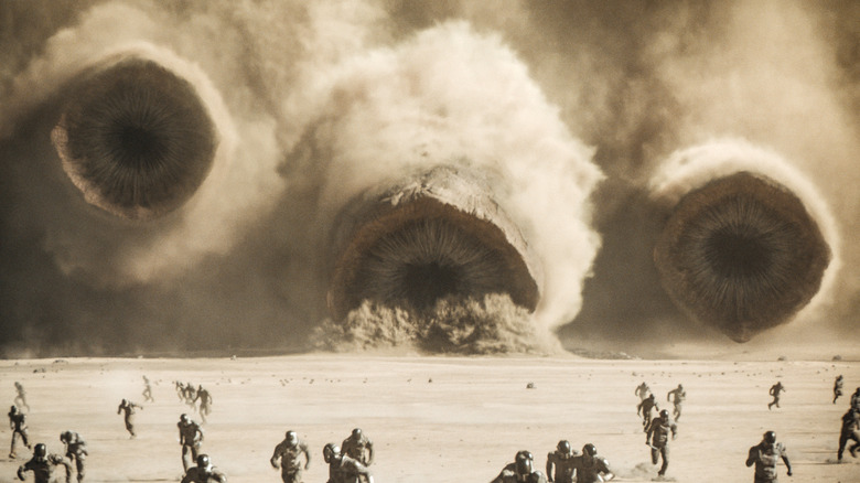 Three sandworms chasing soldiers