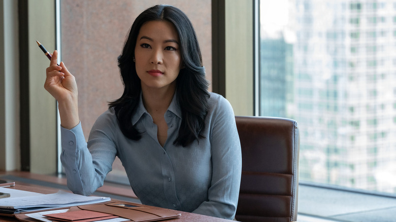 Arden Cho as Ingrid sitting at desk in Partner Track 