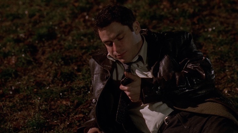 Jimmy McNulty lying on the ground and looking at his badge