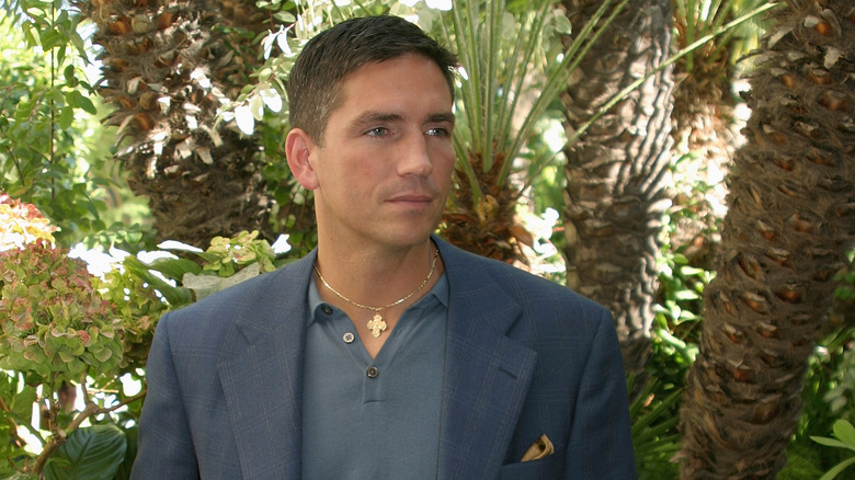 Jim Caviezel standing near palm trees