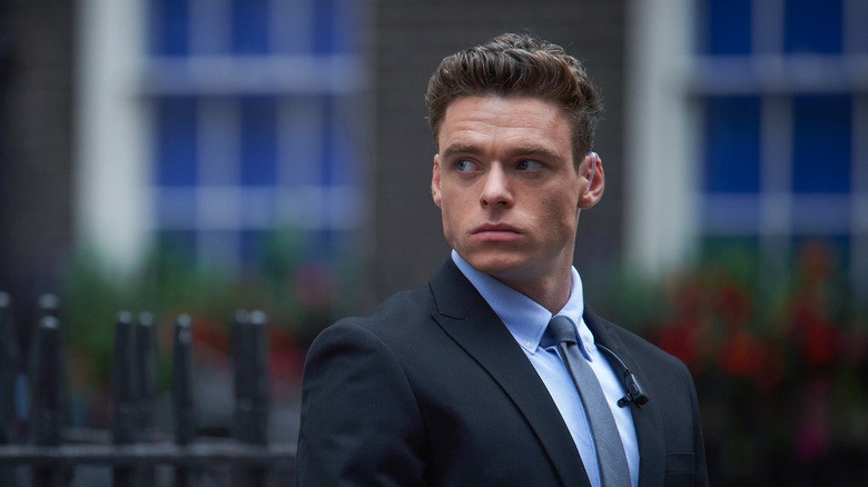 Richard Madden standing in front of a fence in Bodyguard