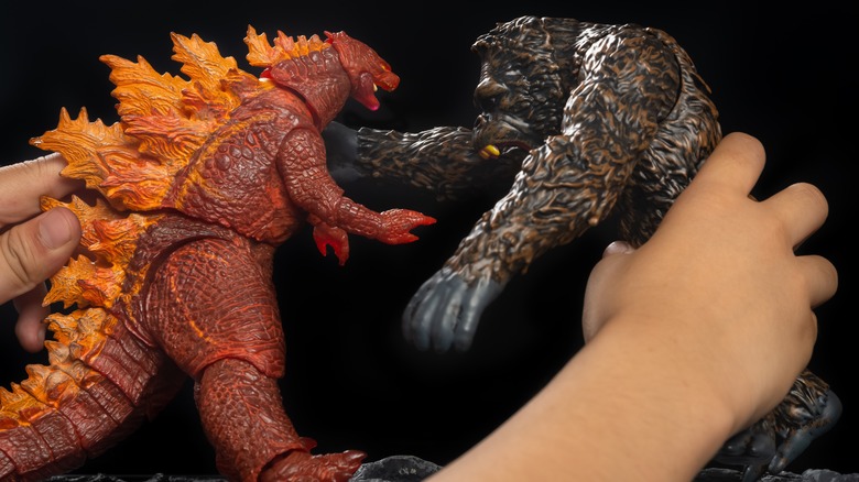 Someone playing with a Godzilla and Kong toy