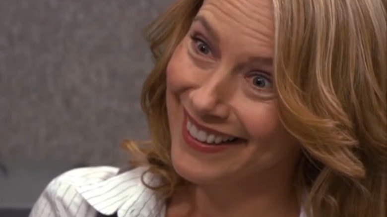 Holly Flax grins exaggeratedly at Michael Scott