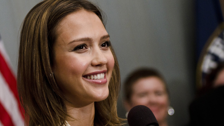 Alba smiling while speaking at a mic