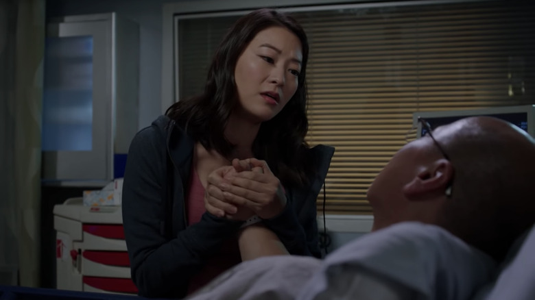 Arden Cho holding the hand of a hospital patient