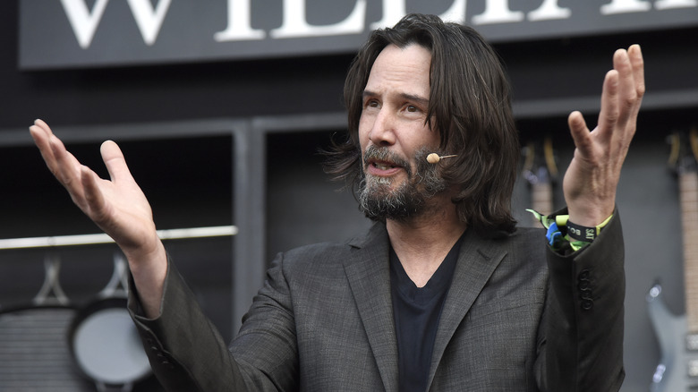 Keanu Reeves holding arms up