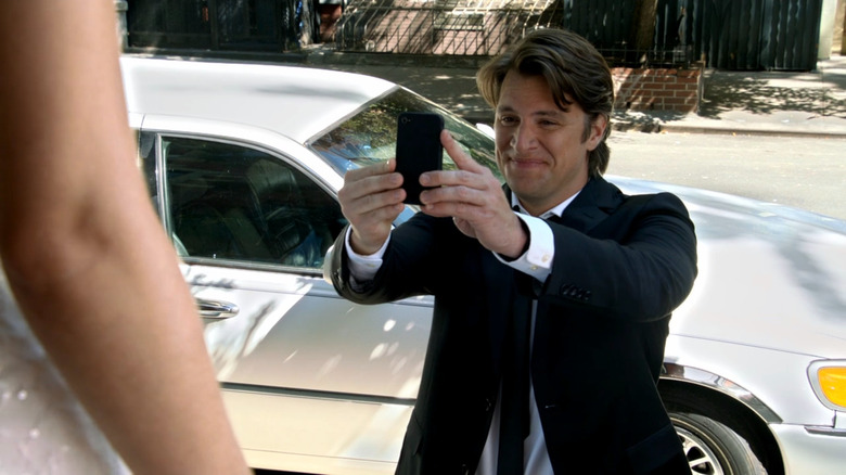 Johnny Evans holds a phone in front of a limo