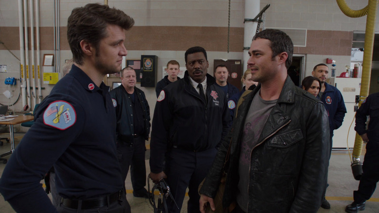 Eric Whaley  and Kelly Severide looks at each other in front of a group of firefighters