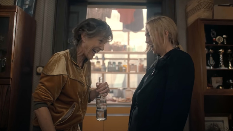 Dasha and Villenelle laugh while she holds a bottle of liquid