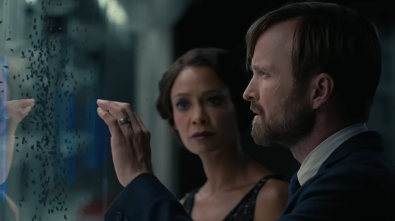 Thandiwe Newton and Aaron Paul looking at bugs on glass in a trailer for Westworld Season 4