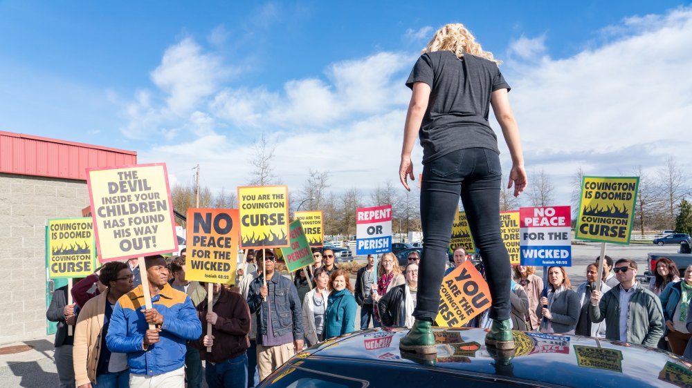 Katharine Langford in Spontaneous, standing in front of picket signs