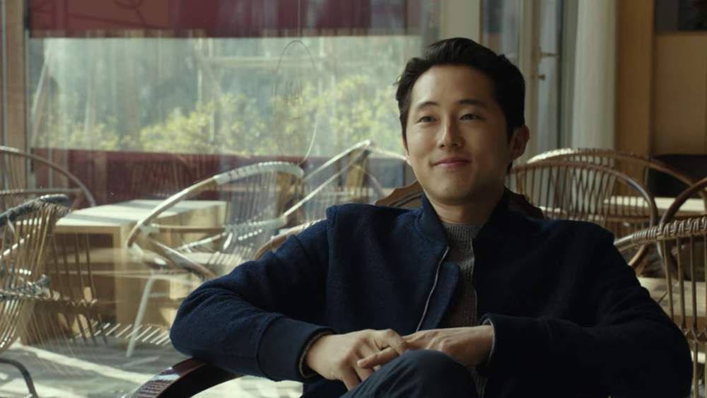 Steven Yeun sitting in a chair