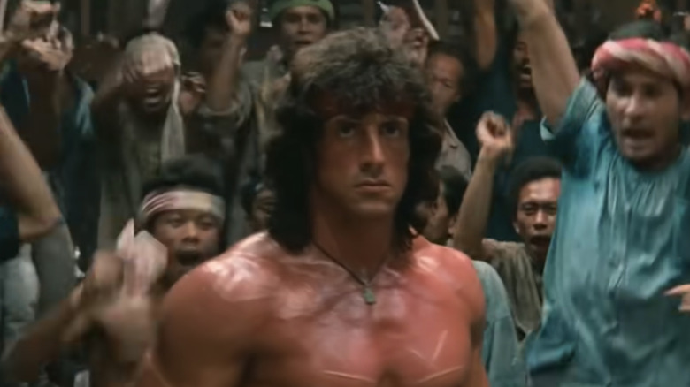 Men cheer behind shirtless Rambo