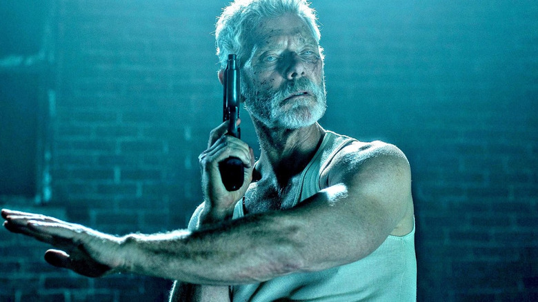 Stephen Lang listening holding gun