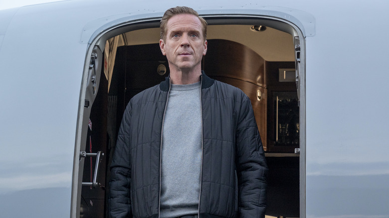 Damian Lewis' Axe stands in the doorway of a plane on Billions