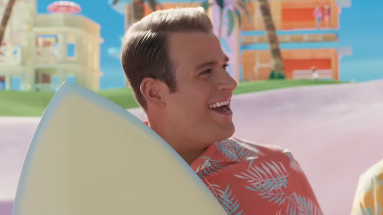 Ken holding surfboard smiling