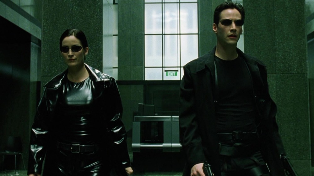 Trinity and Neo enter the government lobby in their cool black outfits in The Matrix