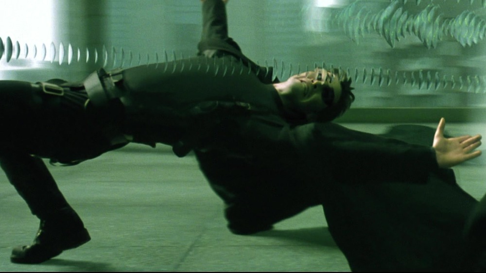 Keanu Reeves as Neo bends backward to dodge a hail of bullets in The Matrix
