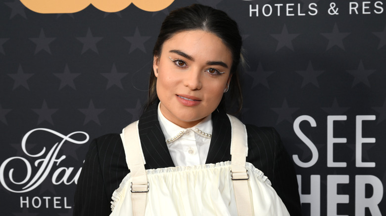 Devery Jacobs smiling in black and white outfit