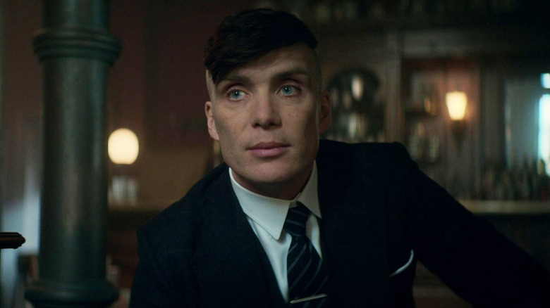 Tommy Shelby leans over table