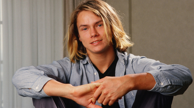 River Phoenix sitting and smiling