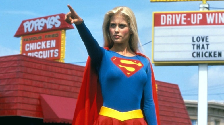 Supergirl pointing with Popeyes behind