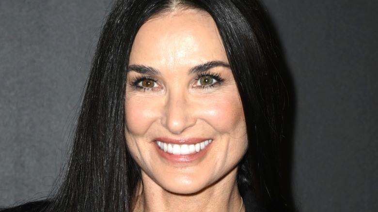 Demi Moore smiling in front of a black background