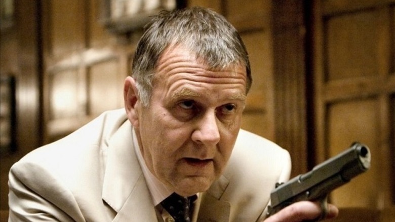 Tom Wilkinson pointing a gun