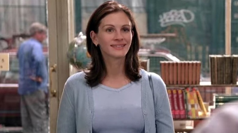 Anna Scott stands in the bookshop and smiles while looking ahead