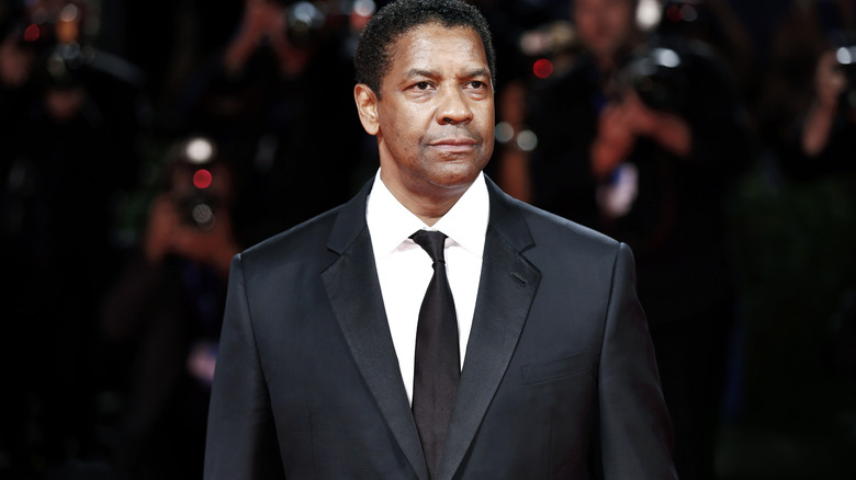 Denzel Washington posing in a suit at an event 