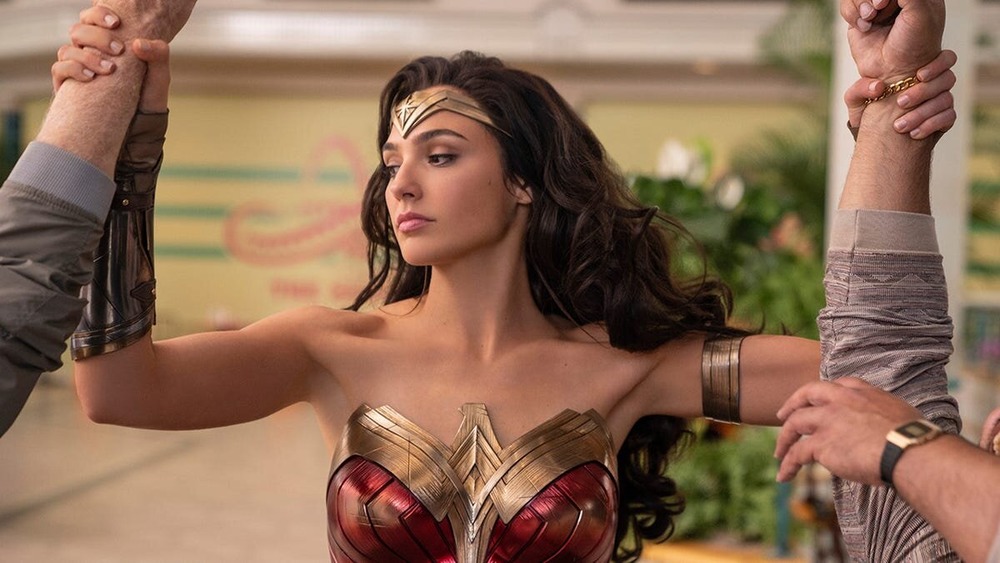 Gal Gadot as Wonder Woman holding wrists of criminals