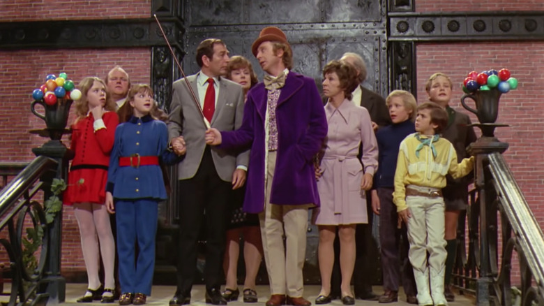 Willy Wonka standing in front of crowd with cane