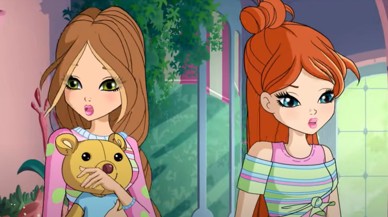 Two Winx characters walk outside, with one holding a bear