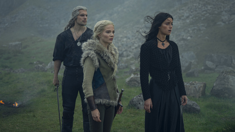 Ciri standing with Geralt and Yennefer in a field