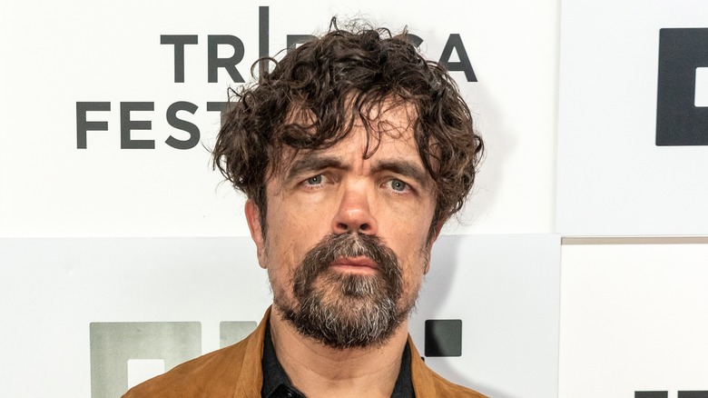 Peter Dinklage stands on a red carpet