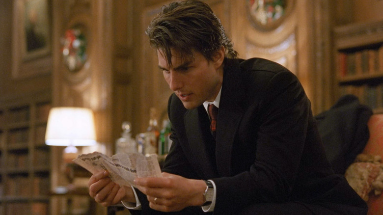 Tom Cruise looking at newspaper clipping