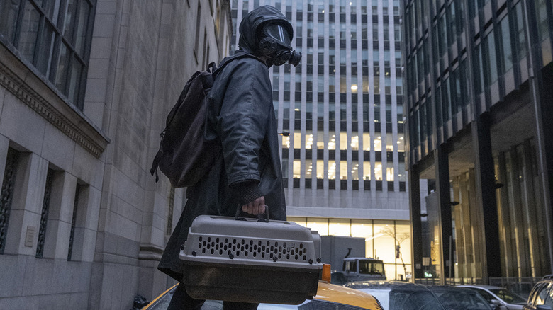 Man in gas mask holding pet carrier