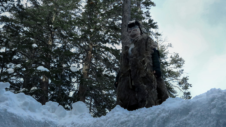 Masked figure stands in snow