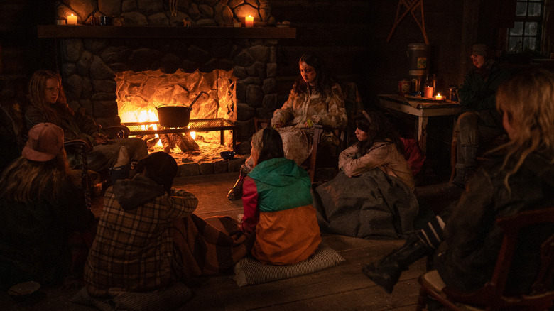 The Yellowjackets sitting by the fireplace inside the cabin