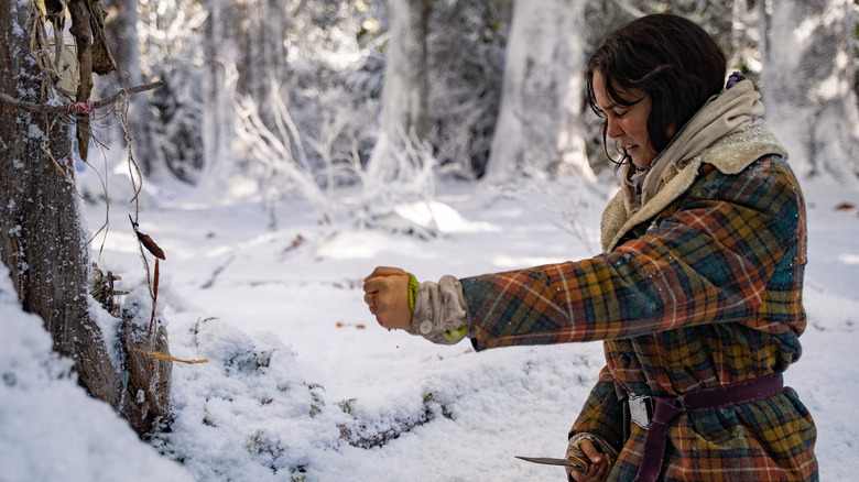 Lottie cutting her hand to a totem in the snowy woods