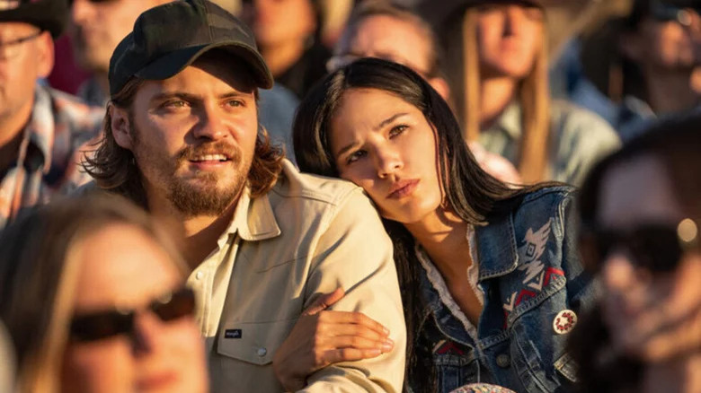 Luke Grimes as Kayce Dutton and Kelsey Asbille as Monica Dutton sitting in a crowd