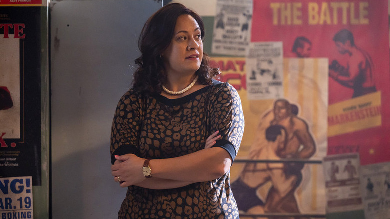 Stacey Leilua as Ata Johnson in front of wrestling posters in Young Rock