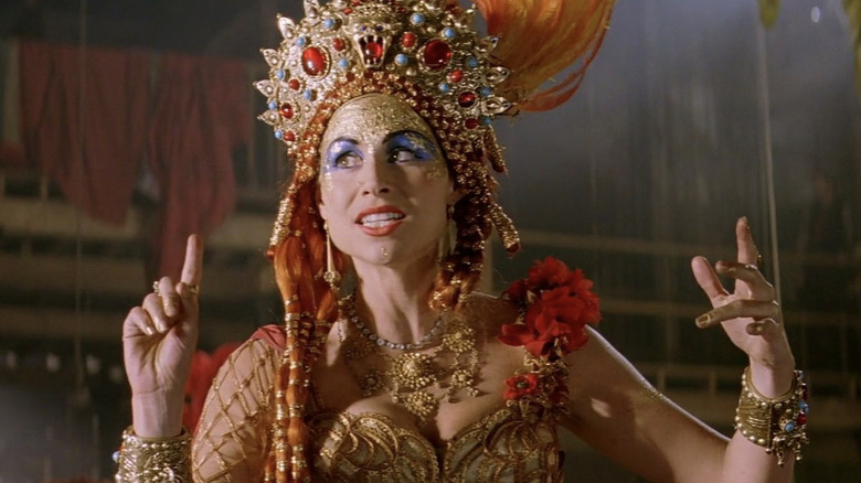 Carlotta raises hands in headdress